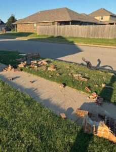 Damaged brick mailbox before rebuild with scattered bricks and debris